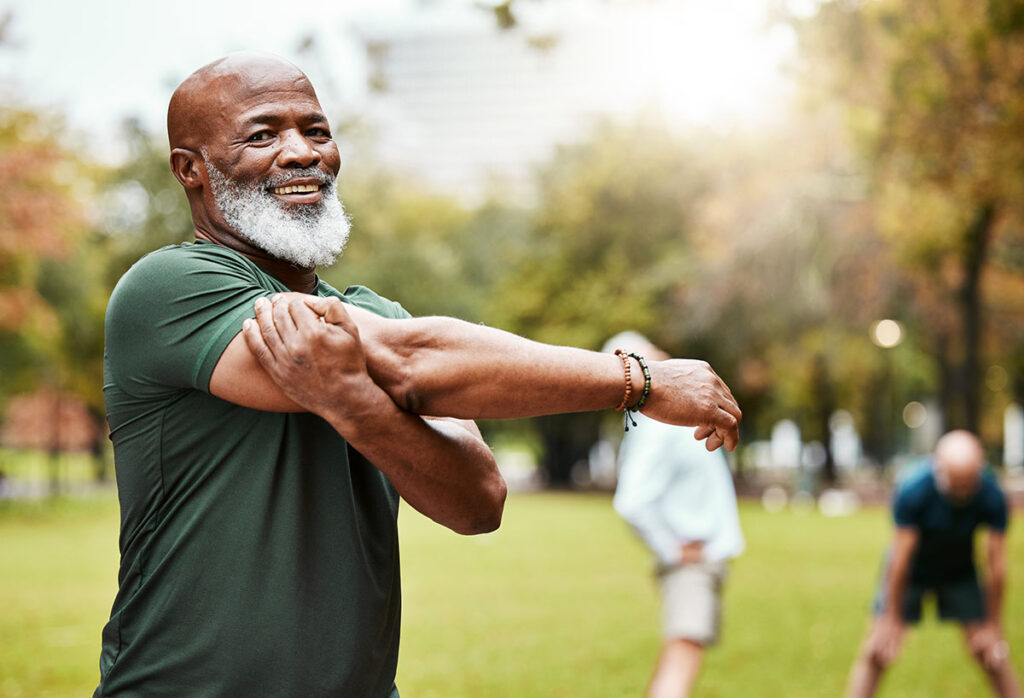 An older man stretching while outdoors before an activity.