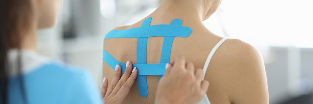 Supportive tape being applied to a patient's spine as a brace.